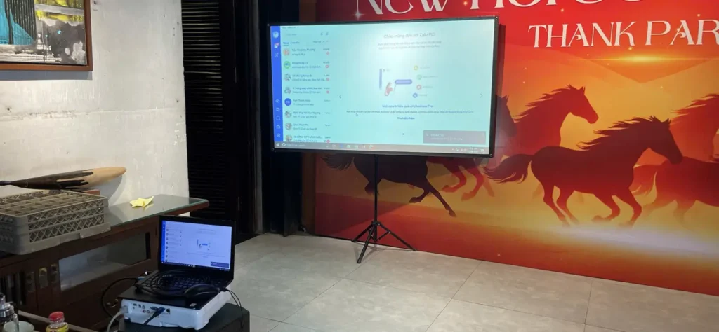 máy chiếu LED 100 inch được sử dụng trong phòng họp với màn hình treo tường và laptop kết nối