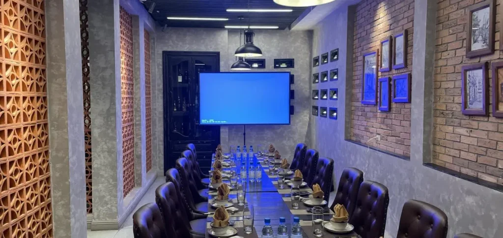 phòng họp hiện đại với bàn tròn, ghế đen và màn hình LED to ở cuối phòng